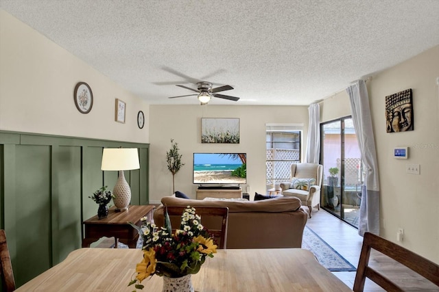 living room featuring a textured ceiling, ceiling fan, and wood finished floors