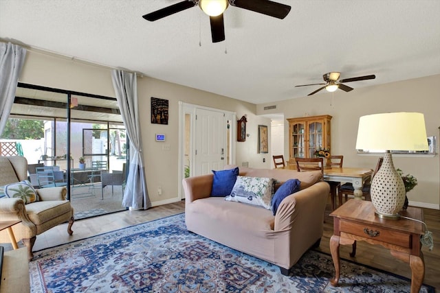 living room featuring a ceiling fan, a textured ceiling, and wood finished floors
