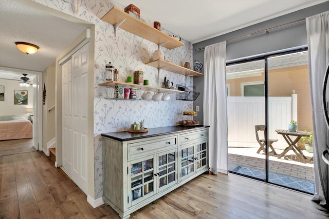 interior space with baseboards, a ceiling fan, hardwood / wood-style flooring, and wallpapered walls
