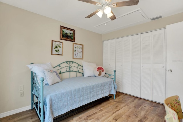bedroom with attic access, baseboards, wood finished floors, visible vents, and a closet