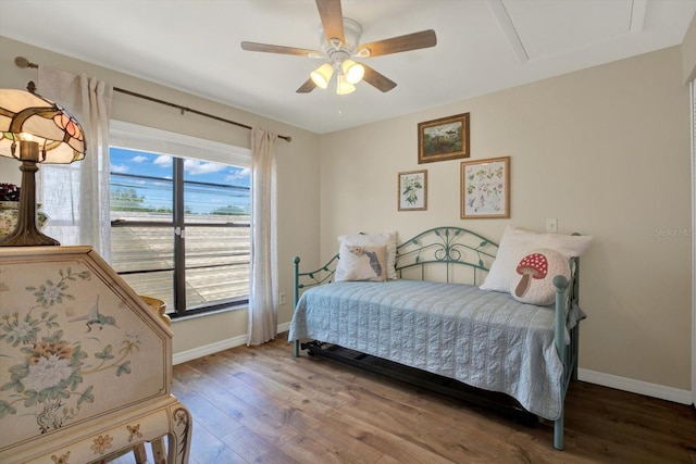 bedroom with baseboards, a ceiling fan, attic access, and wood finished floors