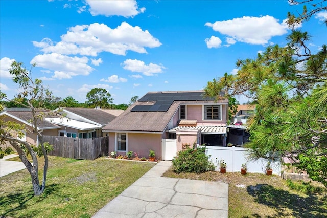 view of front of property featuring a fenced front yard, stucco siding, a front yard, a gate, and solar panels