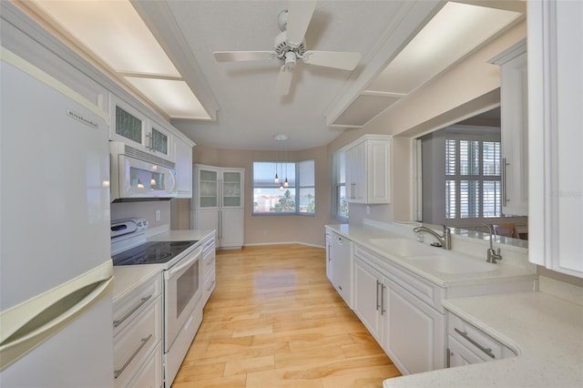 7882 Sailboat Key Blvd S Unit 401, South Pasadena, FL 33707 - kitchen featuring a sink, white appliances, light countertops, light wood-style flooring, and white cabinetry