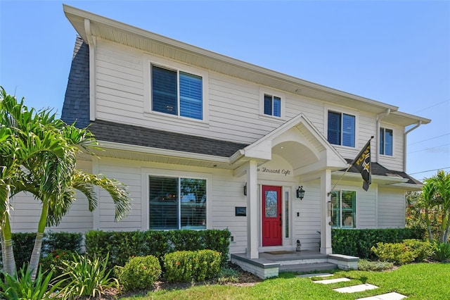 view of front of home with a shingled roof and a front yard