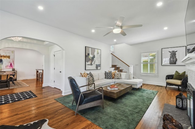 living area featuring ceiling fan, arched walkways, stairs, recessed lighting, and wood finished floors