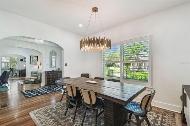 dining space featuring wood finished floors, baseboards, recessed lighting, a chandelier, and arched walkways