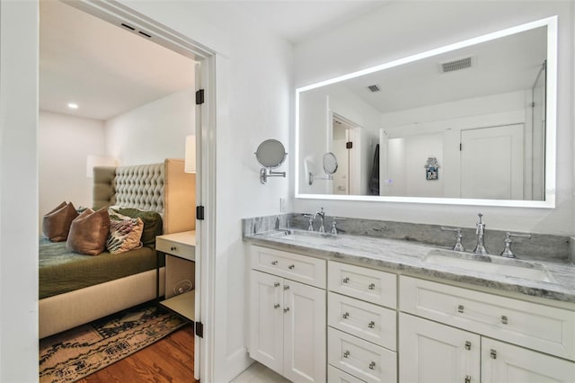 bathroom featuring double vanity, visible vents, a sink, and wood finished floors