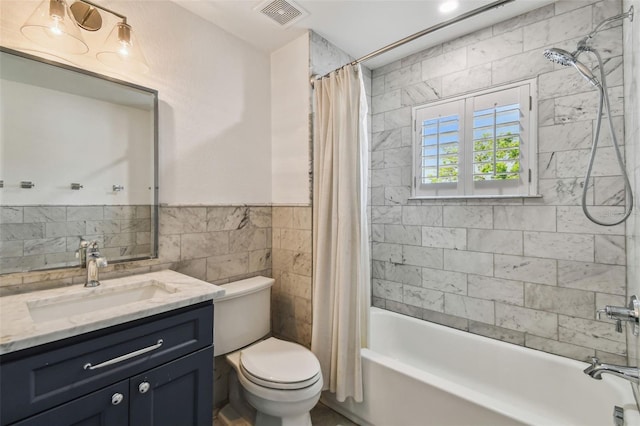 full bath with vanity, shower / tub combo with curtain, toilet, tile walls, and visible vents
