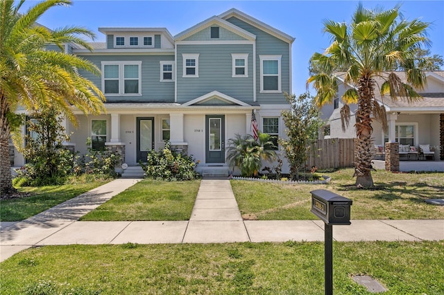 view of front of house featuring fence, a porch, and a front lawn