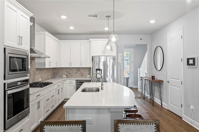 kitchen featuring visible vents, a center island with sink, dark wood finished floors, a sink, and stainless steel appliances