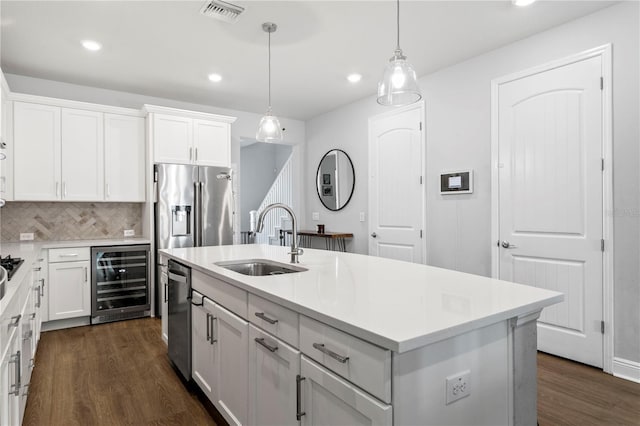 kitchen featuring a sink, beverage cooler, dark wood-type flooring, stainless steel dishwasher, and visible vents