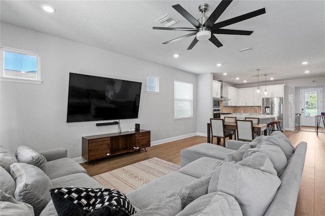 living room featuring light wood-style floors, ceiling fan, recessed lighting, and visible vents