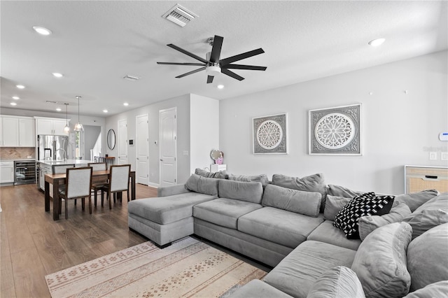 living area featuring visible vents, recessed lighting, dark wood-style flooring, and a ceiling fan