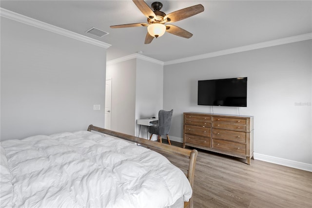 bedroom featuring ceiling fan, visible vents, wood finished floors, baseboards, and ornamental molding