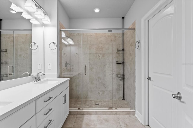 bathroom featuring a sink, tile patterned flooring, a shower stall, and double vanity