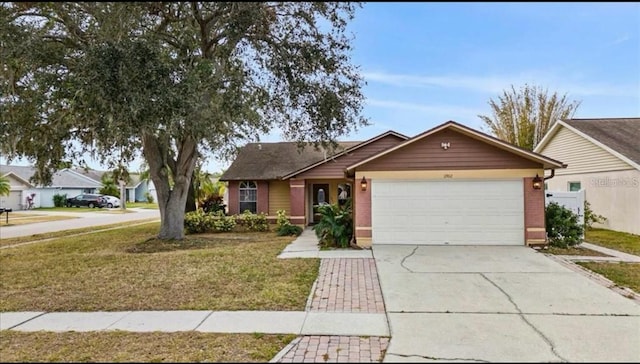 ranch-style house featuring an attached garage, driveway, and a front yard