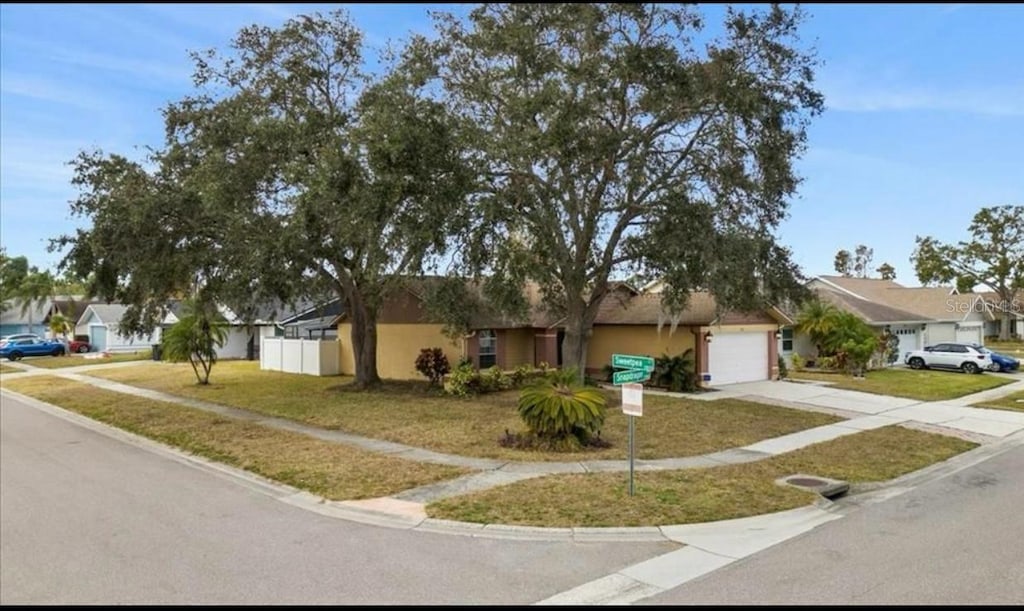 ranch-style house with a garage, fence, a front yard, driveway, and a residential view