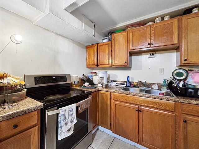 kitchen featuring a sink, stainless steel range with electric stovetop, light tile patterned floors, and brown cabinets