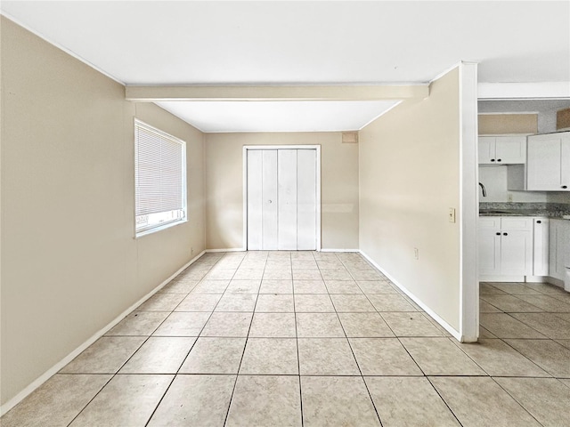 unfurnished bedroom with a closet, baseboards, and light tile patterned flooring