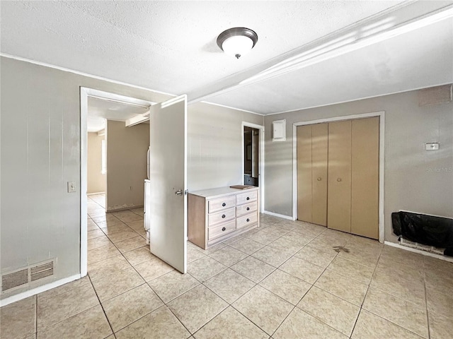 unfurnished bedroom featuring light tile patterned floors, a closet, a textured ceiling, and visible vents