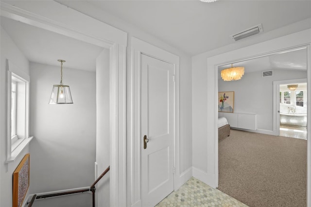 hall with carpet floors, baseboards, and visible vents
