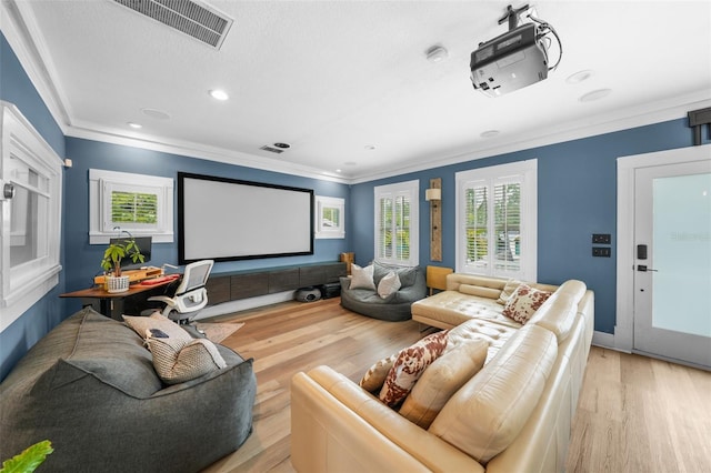 home theater featuring visible vents, ornamental molding, a healthy amount of sunlight, and light wood-style floors