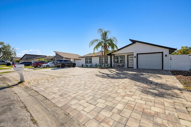 ranch-style house featuring decorative driveway, an attached garage, and fence
