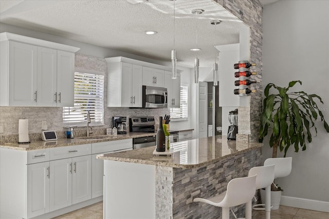kitchen with a sink, a textured ceiling, backsplash, and stainless steel appliances