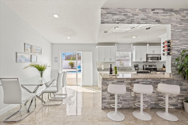 kitchen with appliances with stainless steel finishes, light stone countertops, a textured ceiling, and a wealth of natural light
