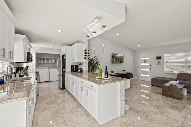 kitchen with decorative backsplash, freestanding refrigerator, open floor plan, a sink, and independent washer and dryer