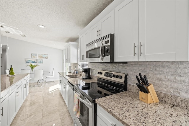kitchen with backsplash, stainless steel appliances, a textured ceiling, and a sink