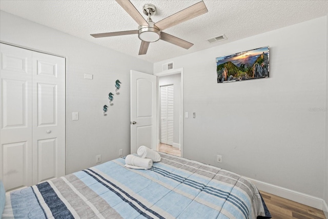 bedroom with light wood finished floors, a textured ceiling, and visible vents