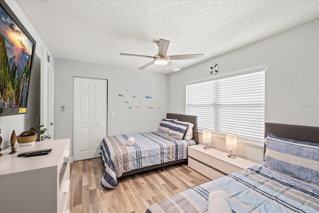 bedroom featuring light wood-style floors, a textured ceiling, and ceiling fan