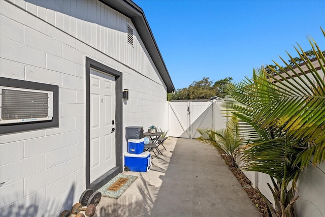 view of exterior entry with fence, a gate, concrete block siding, and a patio area