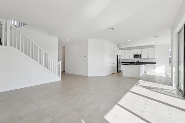 unfurnished living room with recessed lighting, a sink, light tile patterned floors, and stairway
