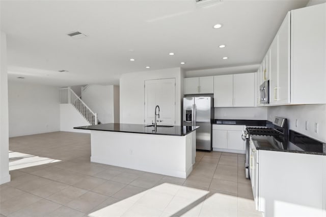 kitchen featuring dark countertops, recessed lighting, white cabinetry, a sink, and stainless steel appliances