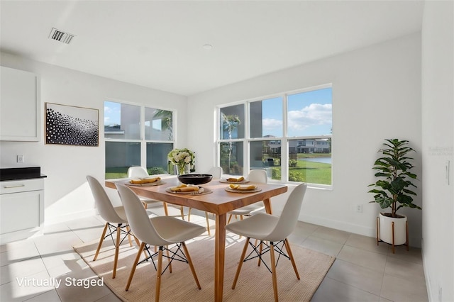 dining space with baseboards, a water view, light tile patterned flooring, and visible vents