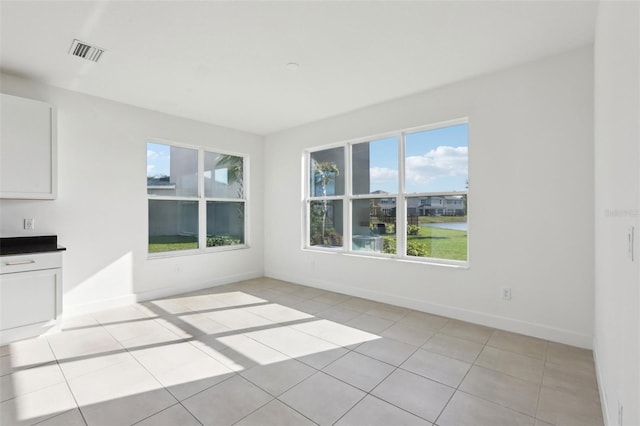 interior space with light tile patterned floors, baseboards, a water view, and visible vents