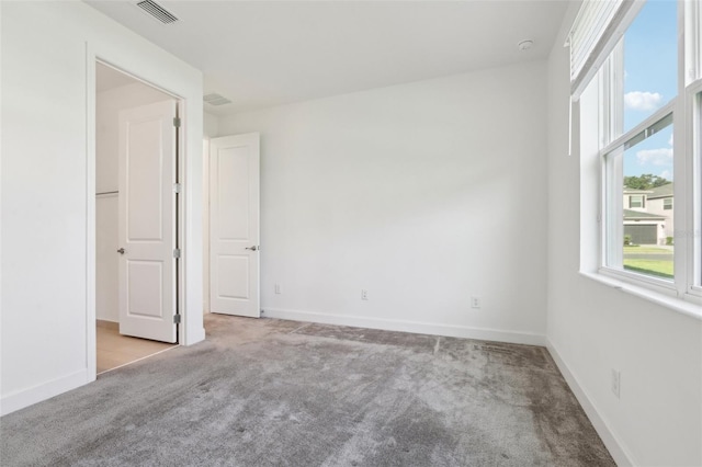 carpeted empty room featuring baseboards and visible vents