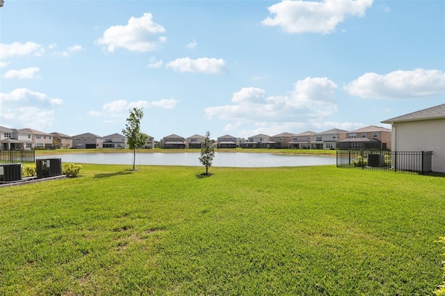 view of yard featuring a residential view, fence, a water view, and cooling unit