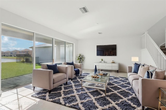 tiled living area with visible vents, stairs, and a water view