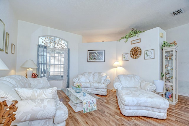 living area with visible vents, baseboards, and wood finished floors