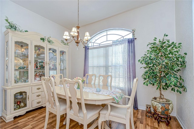 dining area featuring baseboards, a chandelier, and wood finished floors