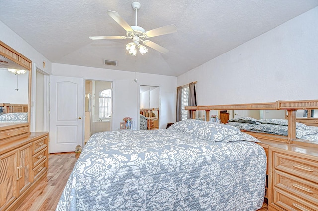 bedroom with visible vents, a textured ceiling, and light wood finished floors