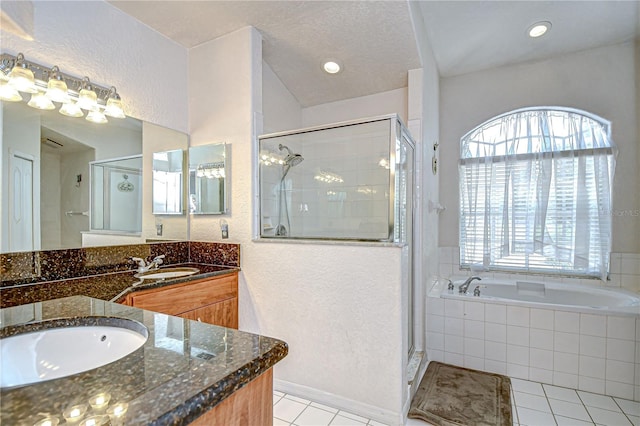 full bath with tile patterned flooring, vanity, a textured wall, a bath, and a shower stall