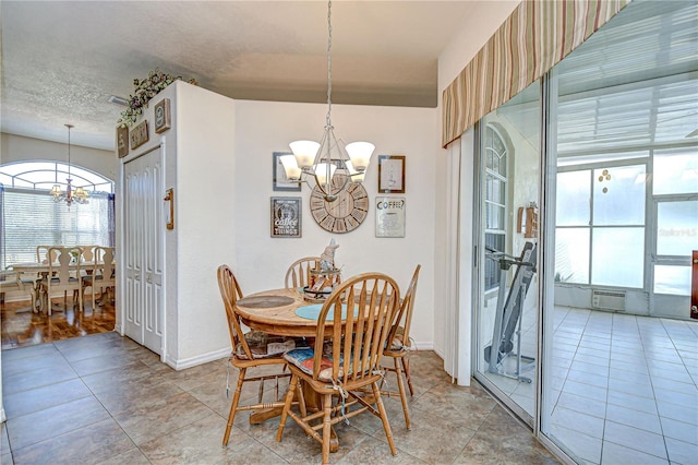 dining space with a textured ceiling, baseboards, an inviting chandelier, and light tile patterned floors