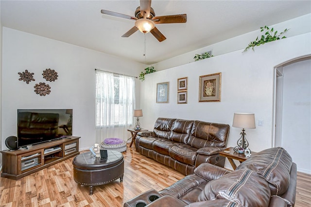 living area featuring arched walkways, a ceiling fan, and light wood-type flooring