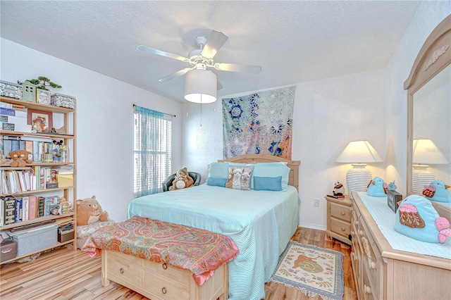 bedroom with a textured ceiling, light wood finished floors, and ceiling fan