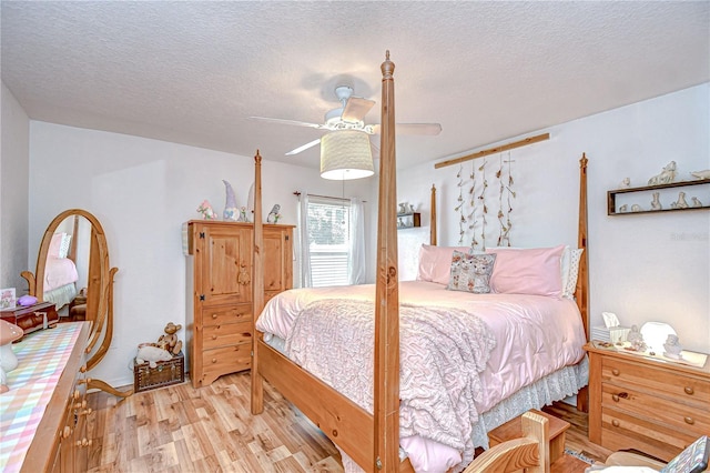 bedroom with a textured ceiling, light wood finished floors, and a ceiling fan