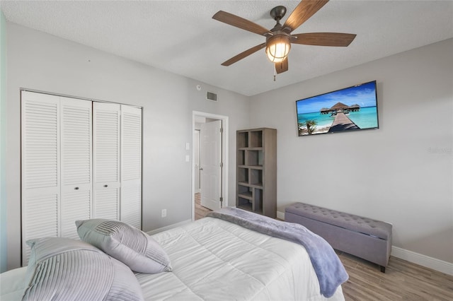 bedroom with visible vents, a closet, baseboards, light wood-style floors, and ceiling fan